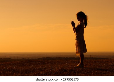 Silhouette of a cute little girl meditating.Little girl meditating - Powered by Shutterstock