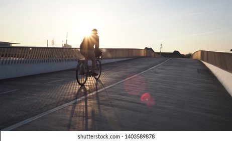 Silhouette of a cyclist on a crossing a bridge against the rising sun - Powered by Shutterstock