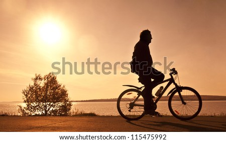 silhouette of the cyclist who rides a bicycle with no hands on r