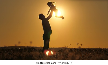 Silhouette dad throws happy little daughter into the sunset sky. Father's day. The child wants to fly above the ground. A parent with a child plays at dawn. Family and childhood concept. Kid jumps on - Shutterstock ID 1902883747