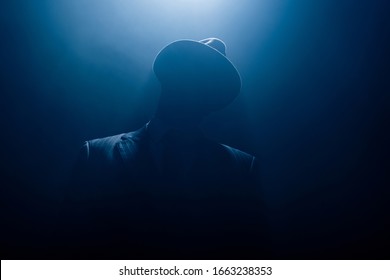 Silhouette Of Dangerous Gangster In Suit And Felt Hat On Dark Background