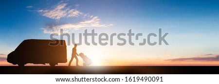 Silhouette Of Delivery Courier With Cardboard Boxes On Trolley Near The Van At Sunset