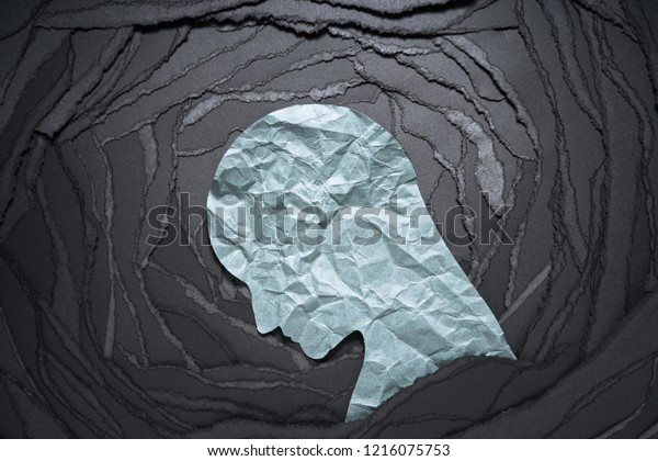 Silhouette of depressed and anxiety person\
head. \
Negative emotion image. Person head shaped paper on black\
torn paper\
background.\
