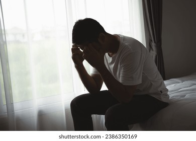 Silhouette depressed man sadly sitting on the bed in the bedroom. Sad asian men suffering depression insomnia awake and sit alone on the bed in bedroom. Depression health people concept. - Powered by Shutterstock