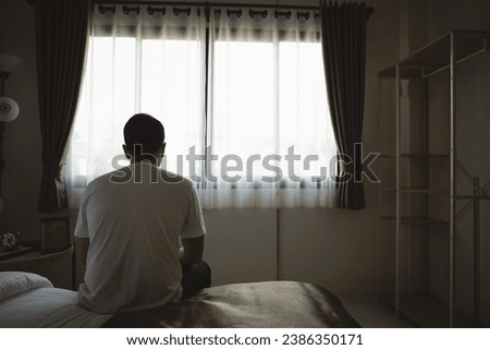 Silhouette depressed man sadly sitting on the bed in the bedroom. Sad asian men suffering depression insomnia awake and sit alone on the bed in bedroom. Depression health people concept.