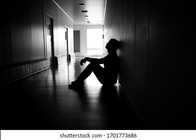 Silhouette of depressed man sitting on walkway of residence building. Sad man, Cry, drama, lonely and unhappy concept. - Shutterstock ID 1701773686
