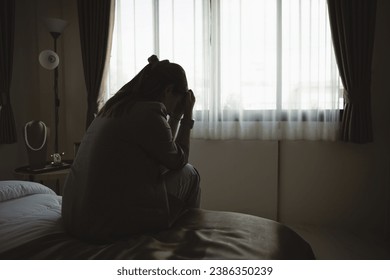 Silhouette depressed woman sadly sitting on the bed in the bedroom. Sad asian women suffering depression insomnia awake and sit alone on the bed in bedroom. Depression health people concept. - Powered by Shutterstock