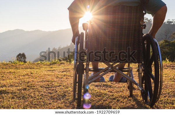 Silhouette Disabled handicapped man is sitting on\
wheelchair at\
sunset.