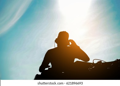 Silhouette of dj mixing outdoor with back sun light - Portrait of disc jockey playing old style vinyl music for people on beach party at sunset - Fun and ,summer,entertainment and fest concept