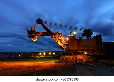 Silhouette Of Drag Line Working On Mine At Afer Sunset With Beautiful Skies,One Side Of Huge Coal Mining Drill Machine Photographed From A Ground ,Mining Site 