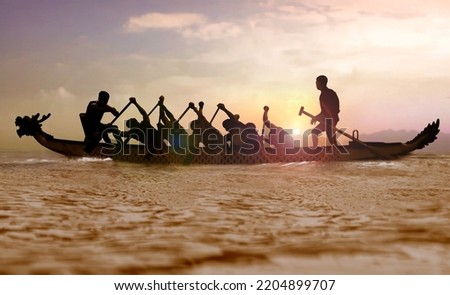 Silhouette of a Dragon boat with people paddling at sunset 