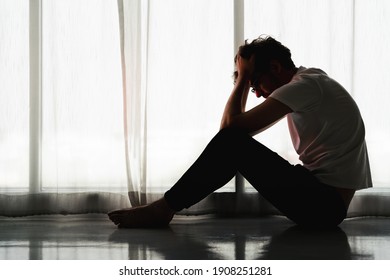 silhouette dramatic portrait of caucasian man sitting alone by window at home looking sorrow with desperate feeing and depressed from unemployment