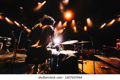silhouette of drummer playing drums on a concert . Club lights, fog, smoke, 