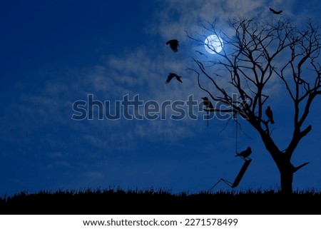 Silhouette of a dry tree outdoors with an old swing broken chain and surrounding crow birds at full moon night.