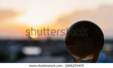 Silhouette of the earth model with the background of the setting sun. Concept of success, hope in life that must move forward.