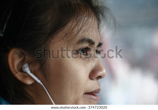Silhouette edge Asian girl\
sitting in the car listening to music from smartphone\
in-Thailand.