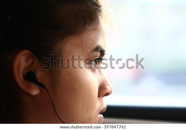 
Silhouette edge Asian girl
sitting in the car listening to music from smartphone
in-Thailand.