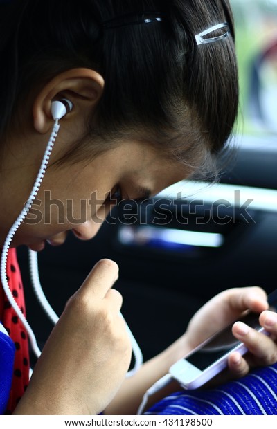 \
Silhouette edge Asian girl\
sitting in the car listening to music from smartphone\
in-Thailand.