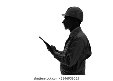 Silhouette of an elderly Caucasian worker in work clothes with a tablet device. - Powered by Shutterstock