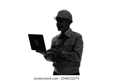 Silhouette of an elderly Caucasian worker in work clothes using a laptop PC.