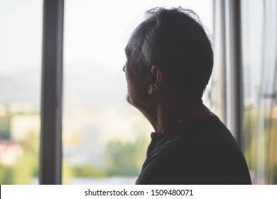 Silhouette of an elderly man on a window background. Old age. Depression pensioner. Retirement loneliness. - Powered by Shutterstock