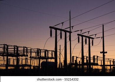Silhouette of electric power lines and power station at sunset