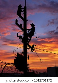 Silhouette Electrical Engineers Working On Electricity Pylon High Tension Power Line Repairs And Maintenance With Blurred Background Beautiful Twilight Sky