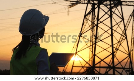silhouette electrician engineer hand holding tablet. electric power industry high voltage. employee electrician works sunset. energy concept. electric tower high voltage. power line. work tablet sun.