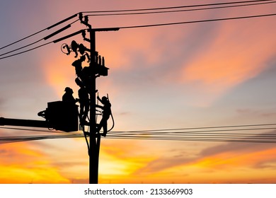 Silhouette of Electrician officer climbs a pole and uses a cable car to maintain a high voltage line system, Shadow of Electrician lineman repairman worker at climbing work on electric post power pole