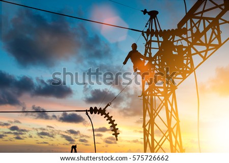 Silhouette electrician work installation of high voltage in high voltage stations safely and systematically over blurred natural background.