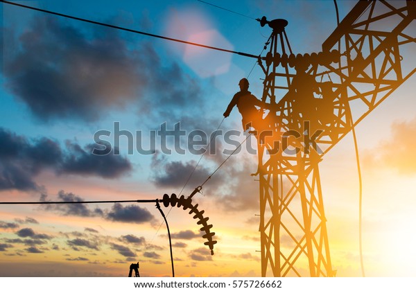 Silhouette electrician work installation of\
high voltage in high voltage stations safely and systematically\
over blurred natural\
background.