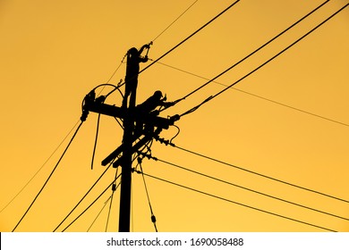 silhouette electrician working on electric power pole 
