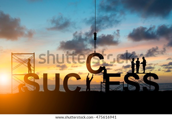 Silhouette employees work as a team to work out
successfully over blurred sky at
sunset
