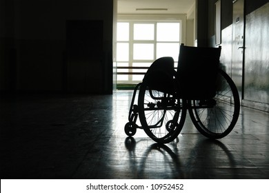 Silhouette of empty wheelchair parked in hospital hallway - Powered by Shutterstock