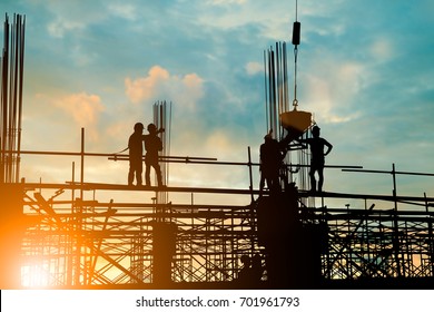 Silhouette of engineer and construction team working safely work load concrete on scaffolding on high rise building. over blurred background sunset pastel for industry background with Light fair  - Shutterstock ID 701961793