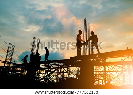 Silhouette of engineer and construction team working at site over blurred background sunset pastel for industry background with Light fair.