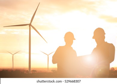 Silhouette Of Engineer And Foreman At Wind Turbine Electricity In Sunset