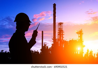 Silhouette Of Engineer And Foreman Working At Petrochemical Oil Refinery In Sunset