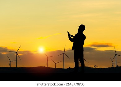 Silhouette of Engineer man checking project at wind farm site on sunset in evening time