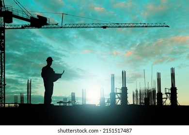 Silhouette Engineer Reading A Building Plan While Working On Construction Site Workers At Sunset Time On A Green Background With Glowing Lights, Industrial Concept.