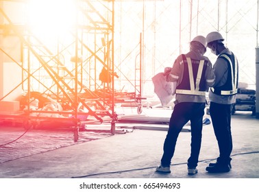 Silhouette engineer in safety protective equipment standing orders for construction crews to work at building construction site. It's a key successfully for business, successful concept