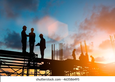Silhouette engineer standing orders for construction and discuss the contract with the sub contractors Heavy industry and safety at work over blurred  background sunset pastel