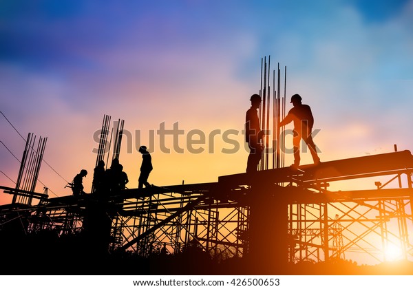 Silhouette engineer standing\
orders for construction crews to work on high ground  heavy\
industry and safety concept over blurred natural background sunset\
pastel