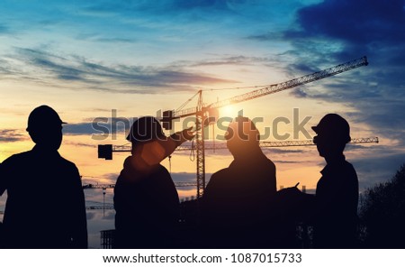Silhouette engineer standing survey work on construction over blurred Worker in  construction site and sunset.