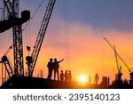 Silhouette of Engineer and worker checking project at construction site, building site with blurred sunset sky in evening time background