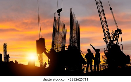 Silhouette of Engineer and worker checking project at building site background, construction site at sunset in evening time - Powered by Shutterstock