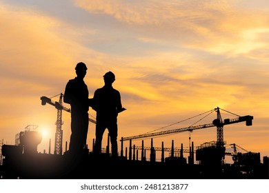 Silhouette of Engineer and worker checking project at building site, Engineer and builders in hardhats discussing on construction site