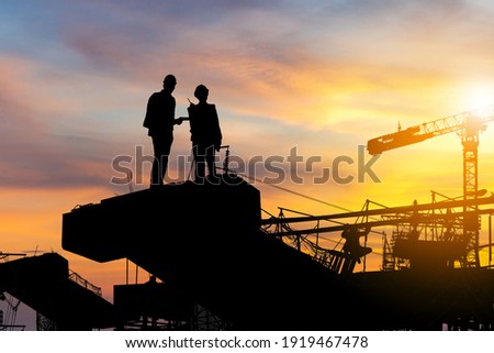 Silhouette of Engineer and worker checking project at building site background, construction site at sunset in evening time.