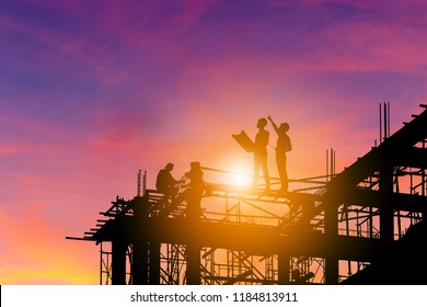 Silhouette of Engineer and worker on building site, construction site with clipping path at sunset in evening time.