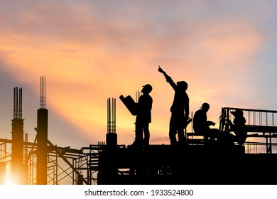 Silhouette of Engineer and worker on building site, construction site at sunset in evening time.